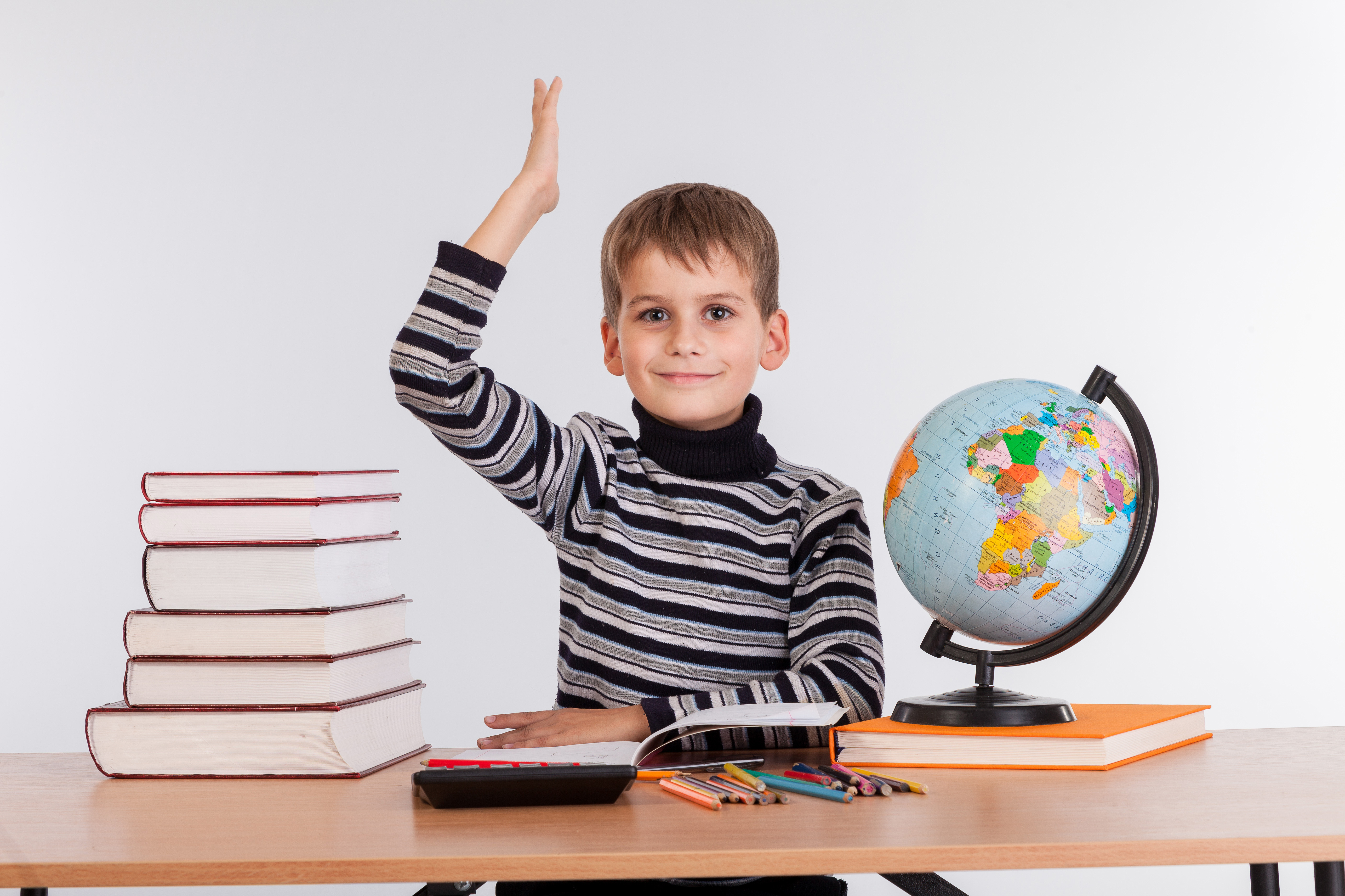 La imagen muestra a un niño con libros, lápices y globo terraqueo