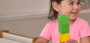 La imagen muestra a una niña pequeña jugando con unos cubos de colores