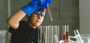 La imagen muestra a un niño experimentando con tubos de ensayo
