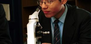La imagen muestra a joven mirando un microscopio