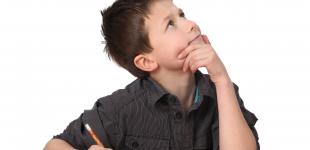 La imagen muestra a un niño con expresión de pensar en una idea y un lápiz en mano sobre un cuaderno